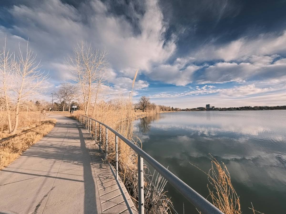 Path along a lake with dry grass and clouds