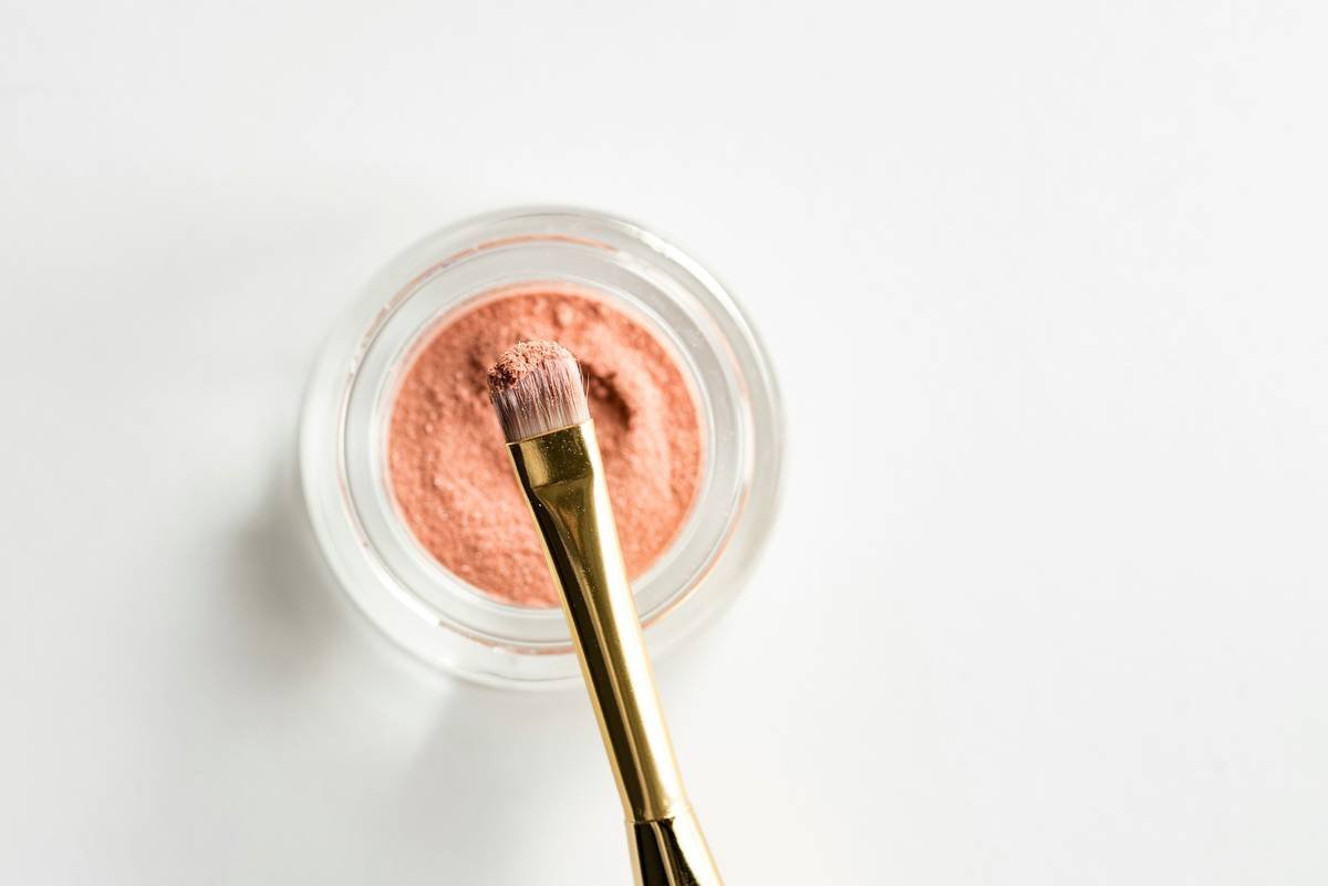 Woman gently applying facial powder makeup for sensitive skin with a soft brush on clean, calm skin